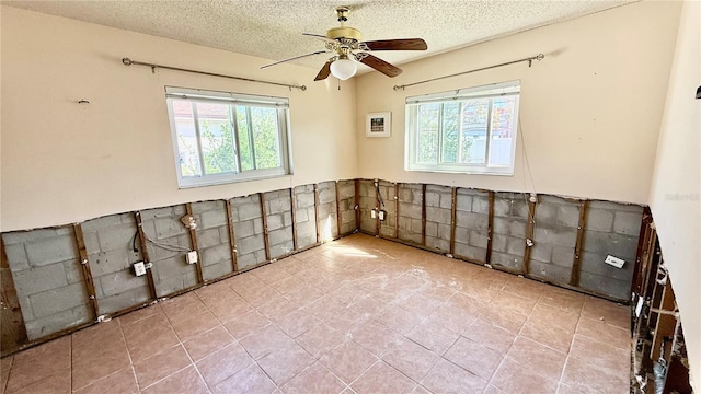 empty room with ceiling fan and a textured ceiling