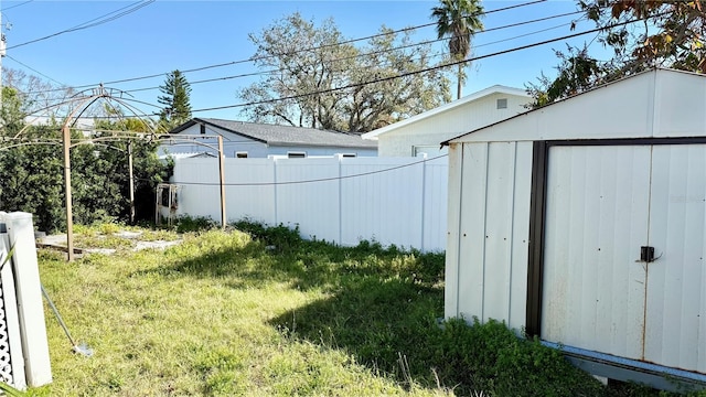 view of yard featuring a shed, an outdoor structure, and fence