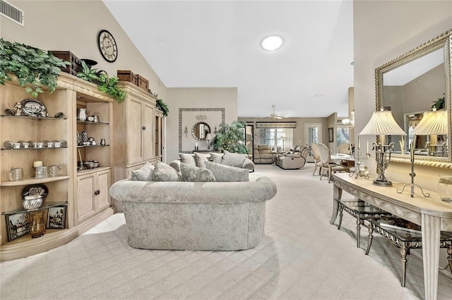 living room with high vaulted ceiling, light colored carpet, visible vents, and ceiling fan