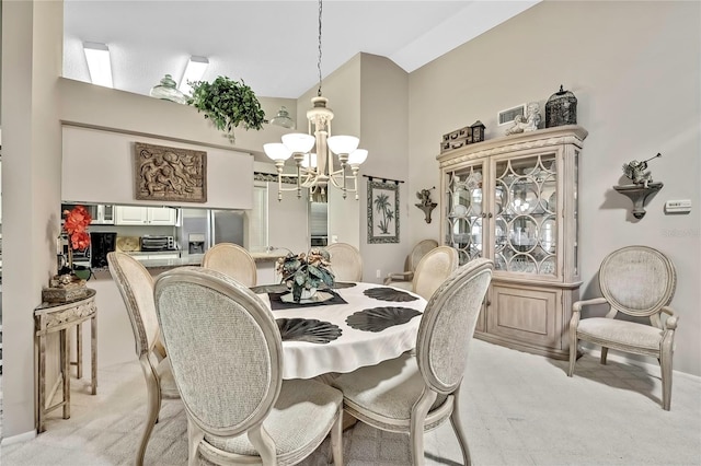 dining area with light carpet, an inviting chandelier, and high vaulted ceiling