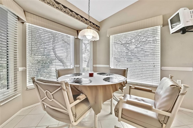 tiled dining space featuring lofted ceiling, plenty of natural light, and baseboards