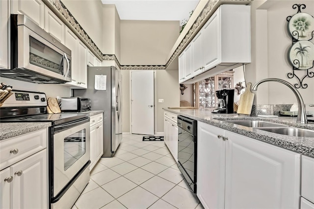 kitchen featuring appliances with stainless steel finishes, light tile patterned flooring, a sink, and white cabinets