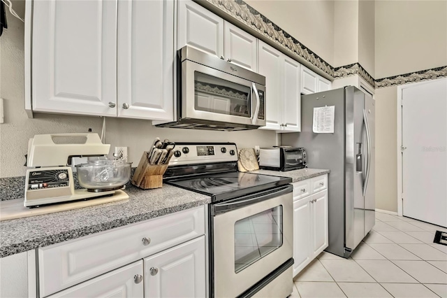 kitchen with light tile patterned floors, appliances with stainless steel finishes, and white cabinets