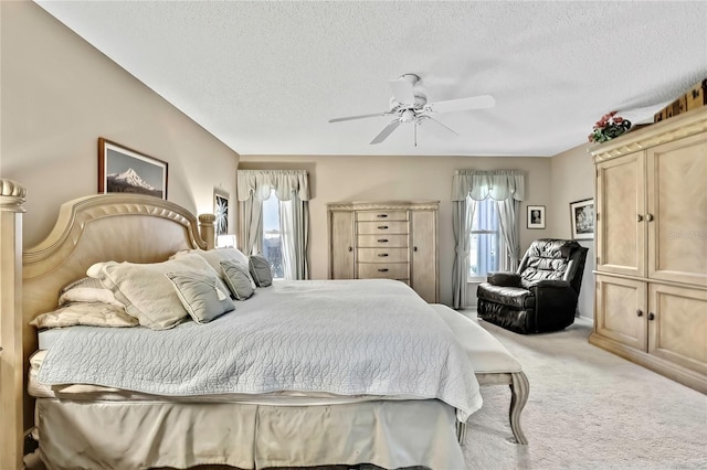 bedroom with a textured ceiling, ceiling fan, multiple windows, and carpet flooring