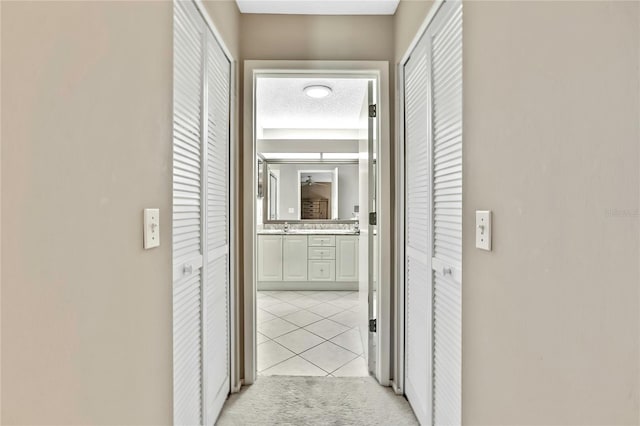 hall with light carpet, light tile patterned flooring, and a textured ceiling