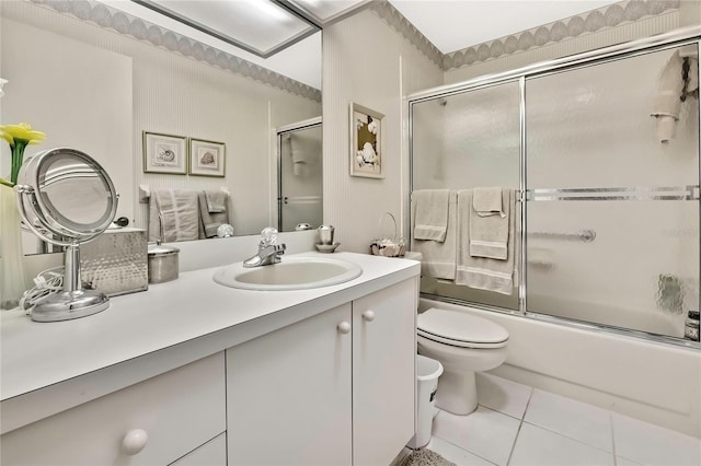 bathroom featuring combined bath / shower with glass door, vanity, toilet, and tile patterned floors