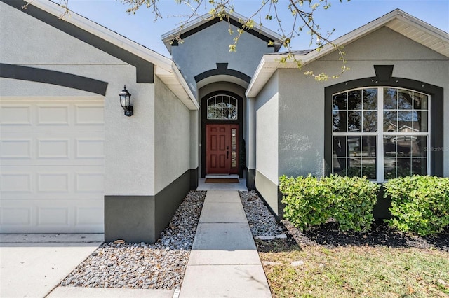 doorway to property featuring an attached garage and stucco siding