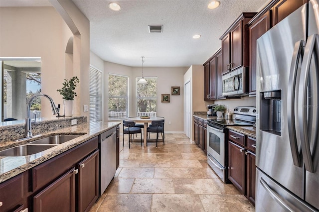 kitchen with light stone counters, stone tile floors, stainless steel appliances, a sink, and visible vents