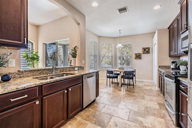 kitchen with stone tile floors, baseboards, visible vents, stainless steel appliances, and a sink