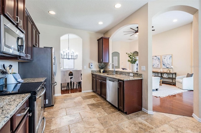 kitchen featuring appliances with stainless steel finishes, a sink, dark brown cabinets, and ceiling fan with notable chandelier