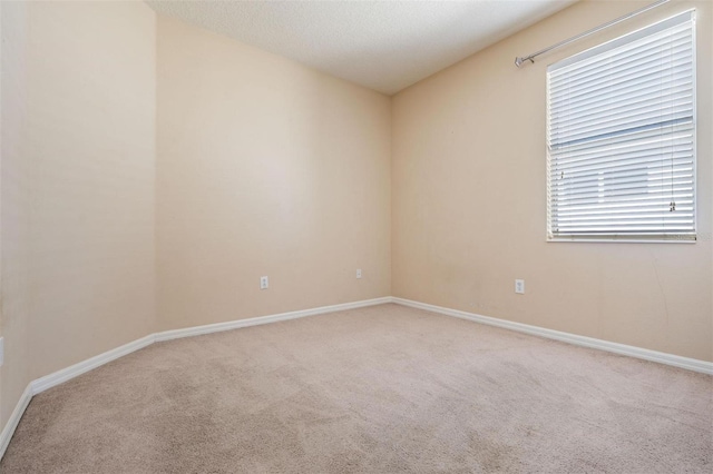 carpeted spare room with a textured ceiling and baseboards