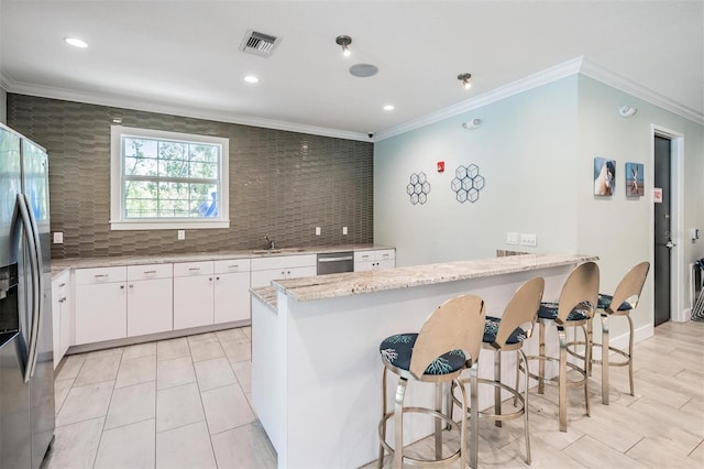 kitchen featuring ornamental molding, light stone counters, a peninsula, stainless steel appliances, and backsplash