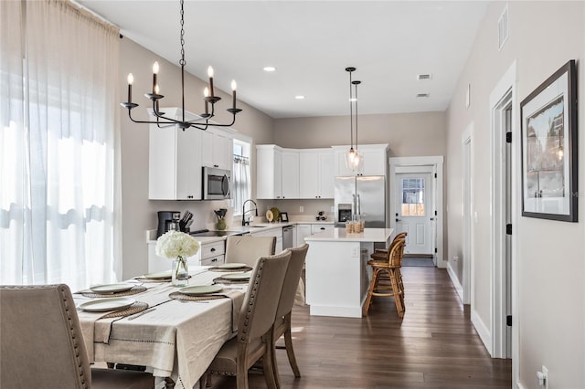 dining area featuring dark wood-style floors, an inviting chandelier, visible vents, and a healthy amount of sunlight