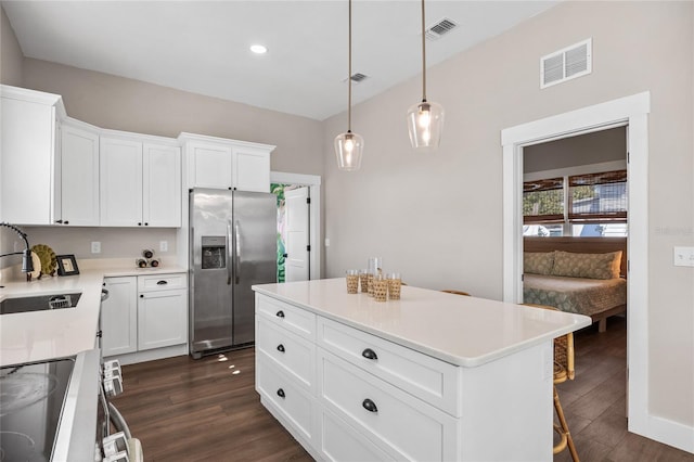 kitchen featuring visible vents, a kitchen island, appliances with stainless steel finishes, light countertops, and a sink