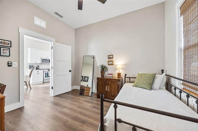 bedroom with multiple windows, wood finished floors, visible vents, and baseboards