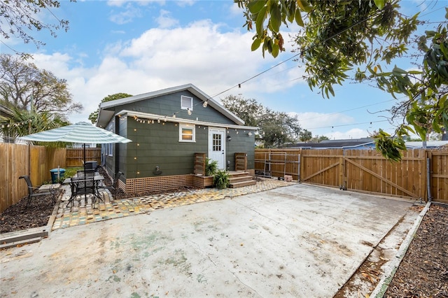 rear view of property with a gate, a patio area, and fence