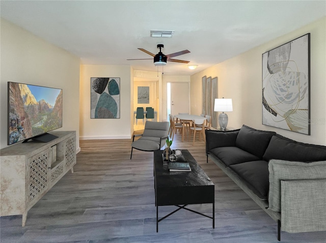 living room featuring baseboards, ceiling fan, visible vents, and wood finished floors