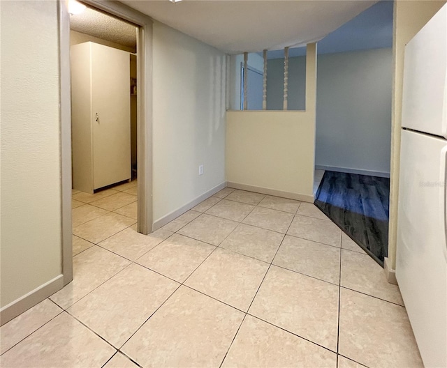 hall featuring baseboards and light tile patterned flooring