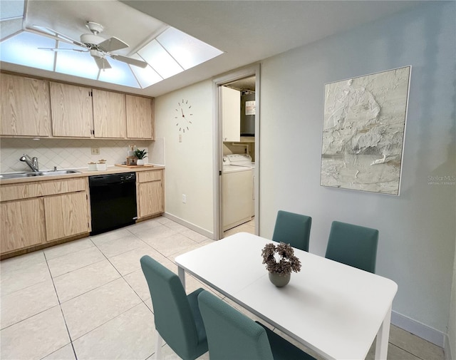 dining room featuring a skylight, baseboards, washer and clothes dryer, a ceiling fan, and light tile patterned flooring