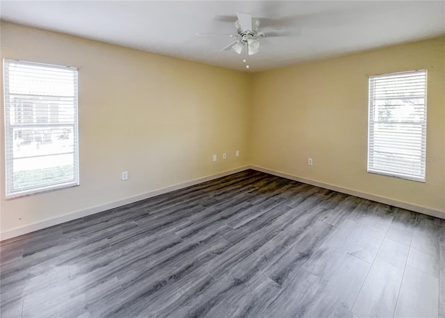 unfurnished room with dark wood finished floors, a ceiling fan, and baseboards