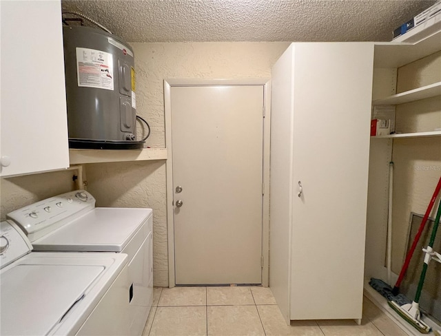 laundry area featuring water heater, a textured wall, separate washer and dryer, and cabinet space