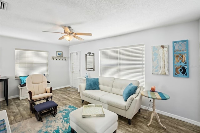 living room with ceiling fan, baseboards, a textured ceiling, and wood finished floors