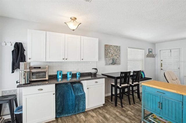 kitchen featuring wood finished floors, white cabinets, a textured ceiling, blue cabinets, and tasteful backsplash