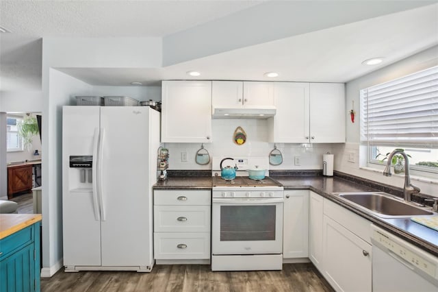 kitchen with white appliances, white cabinets, under cabinet range hood, and a sink