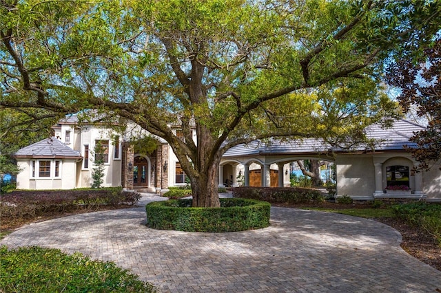 view of front facade featuring stone siding, decorative driveway, and stucco siding