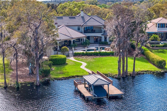 exterior space with a patio, boat lift, a water view, a lawn, and an outdoor pool