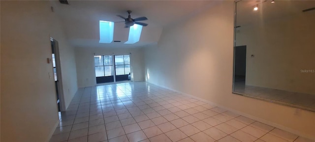 spare room with light tile patterned floors, visible vents, a ceiling fan, baseboards, and lofted ceiling with skylight