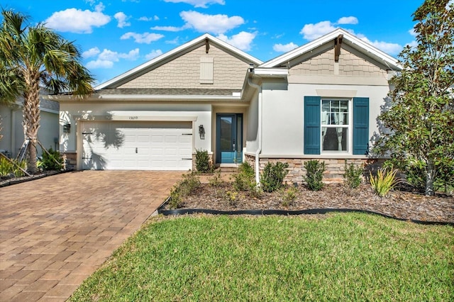 view of front of property featuring an attached garage, stone siding, decorative driveway, stucco siding, and a front yard