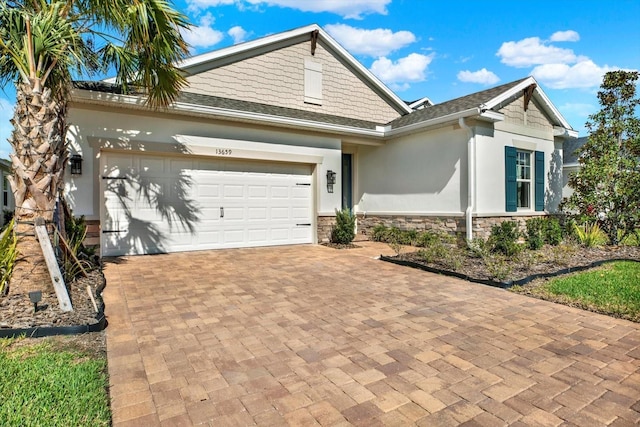 view of front of home featuring a garage, stone siding, decorative driveway, and stucco siding