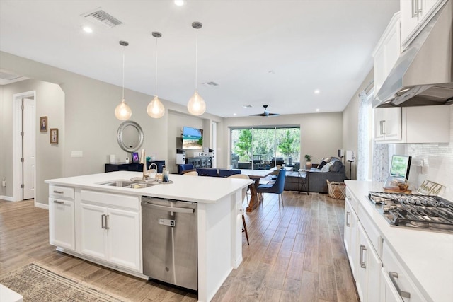 kitchen with under cabinet range hood, a sink, visible vents, open floor plan, and appliances with stainless steel finishes