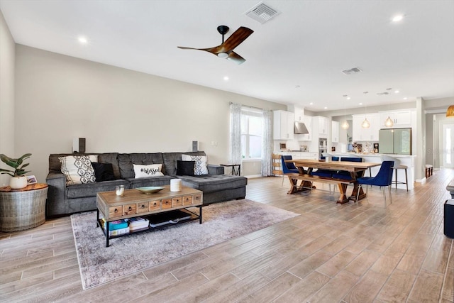 living room with light wood-style floors, visible vents, and recessed lighting