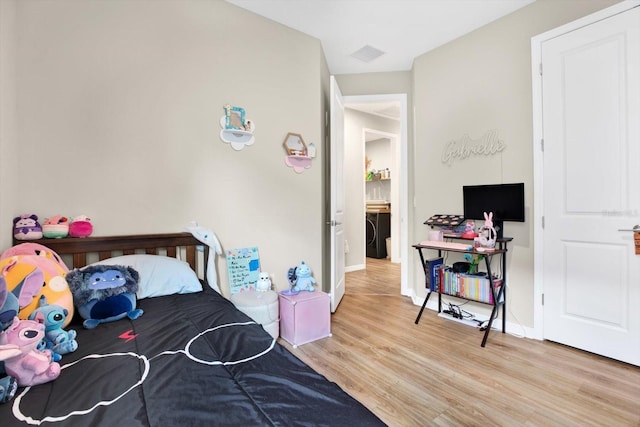 bedroom with washer / dryer, visible vents, baseboards, and wood finished floors