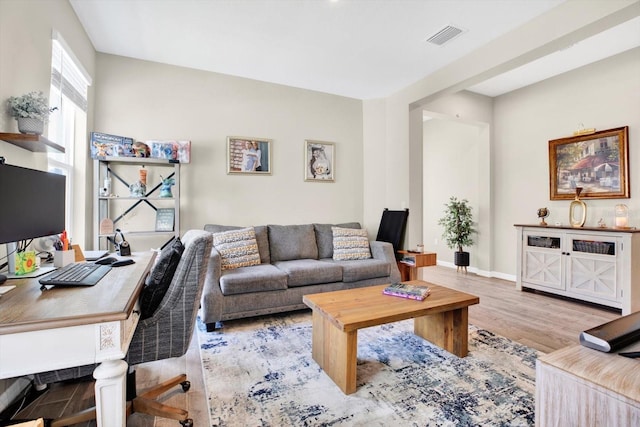 living room with visible vents, baseboards, and wood finished floors