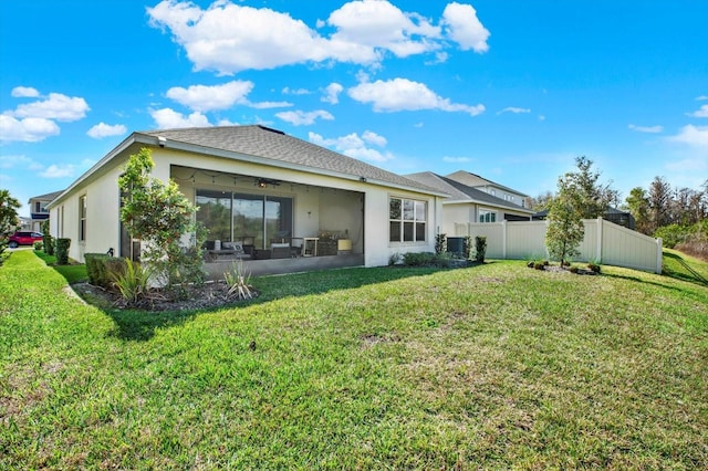 back of house with a yard, central air condition unit, stucco siding, a sunroom, and fence