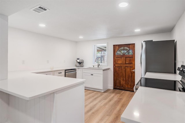 kitchen featuring white cabinets, a peninsula, appliances with stainless steel finishes, and light countertops