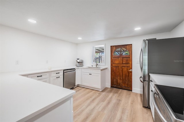 kitchen featuring light countertops, appliances with stainless steel finishes, light wood-style floors, white cabinetry, and a sink