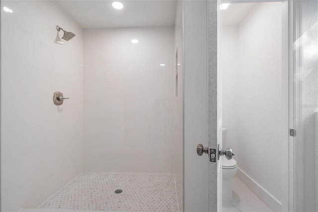 bathroom with a tile shower and toilet