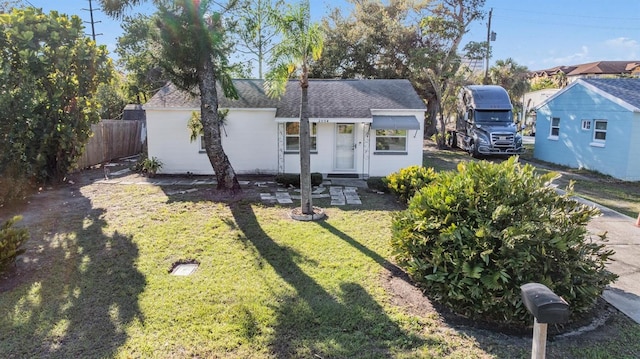 view of front of home featuring a shingled roof, a front yard, and fence