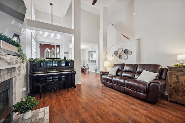 living room with dark wood-type flooring, a tiled fireplace, and baseboards