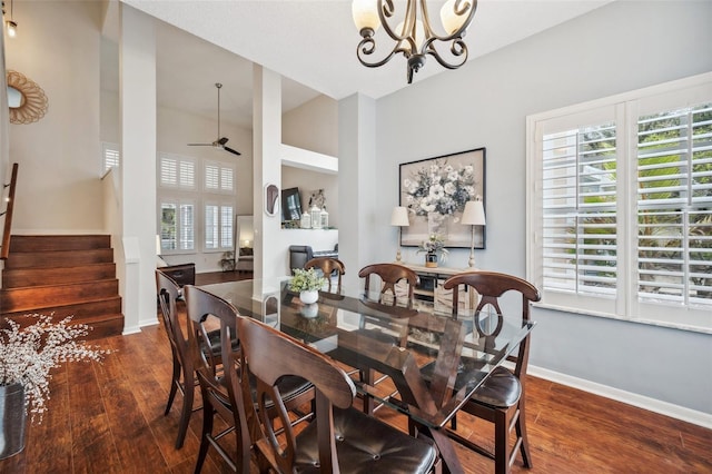 dining space featuring dark wood-style floors, stairway, baseboards, and ceiling fan with notable chandelier