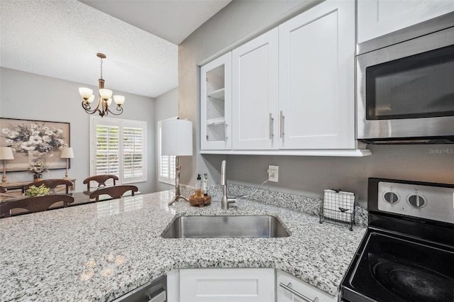 kitchen with stainless steel appliances, glass insert cabinets, a sink, and white cabinetry