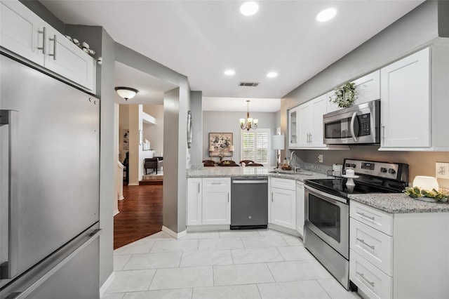 kitchen with stainless steel appliances, hanging light fixtures, a sink, and white cabinetry