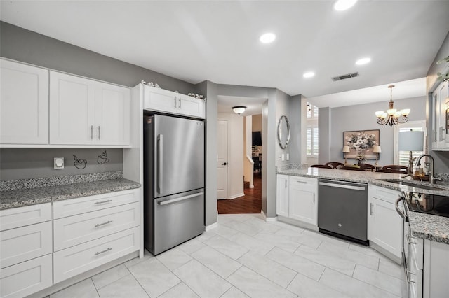 kitchen with appliances with stainless steel finishes, a sink, visible vents, and white cabinets