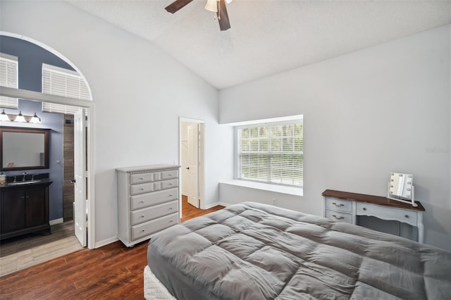 bedroom featuring dark wood-style floors, connected bathroom, vaulted ceiling, and baseboards