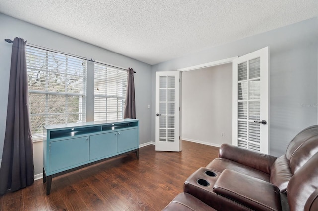 living area featuring french doors, dark wood finished floors, a textured ceiling, and baseboards