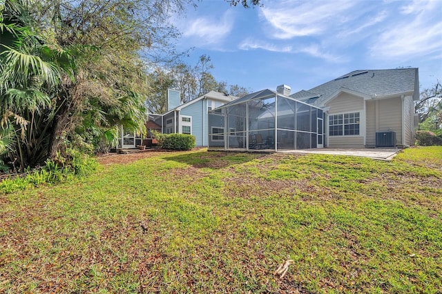 rear view of house with a patio area, a lawn, a chimney, and central AC unit